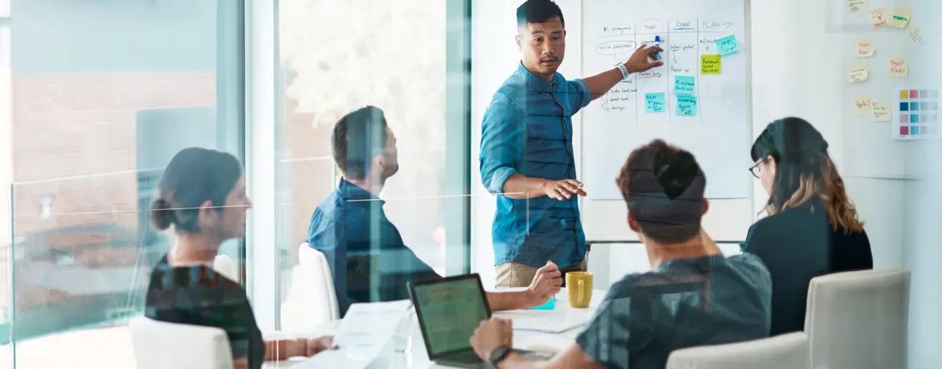 Frau zeigt anderen Personen etwas auf dem Monitor